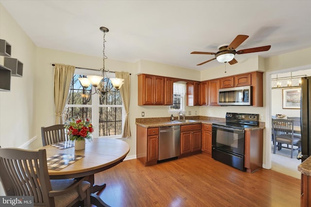 kitchen featuring dark stone countertops, decorative light fixtures, sink, appliances with stainless steel finishes, and hardwood / wood-style floors