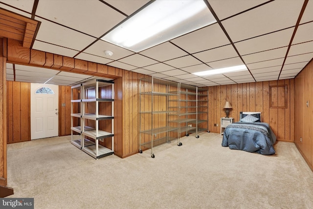 unfurnished bedroom with a drop ceiling, wooden walls, and carpet flooring