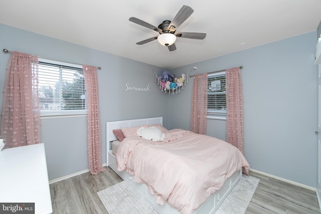 bedroom featuring light wood finished floors, baseboards, and a ceiling fan