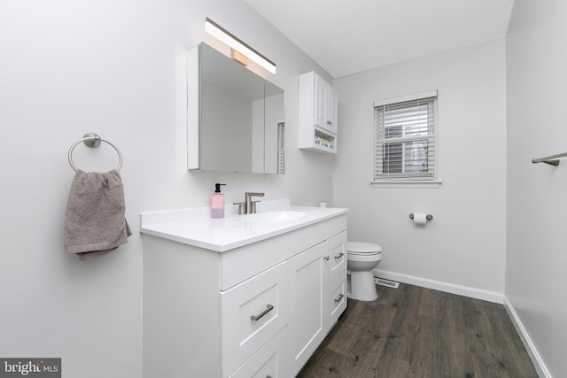 bathroom with toilet, vanity, baseboards, and wood finished floors