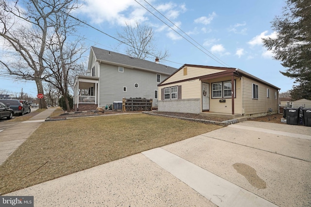 view of front of property with covered porch, brick siding, and a front yard