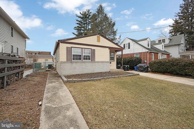 bungalow-style house featuring central AC unit, fence, a front lawn, and brick siding