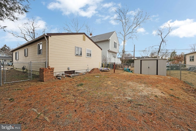 view of side of property featuring a fenced backyard, a gate, a storage unit, and an outdoor structure