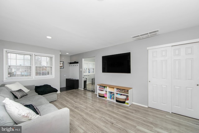 living area featuring light wood-style floors, visible vents, and baseboards