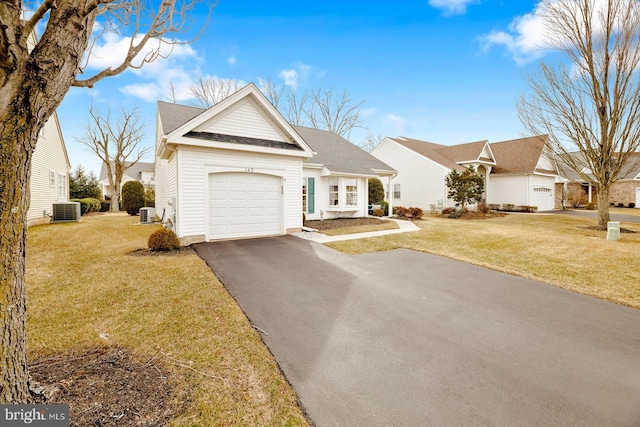 view of front of home with a front lawn, cooling unit, driveway, roof with shingles, and a garage