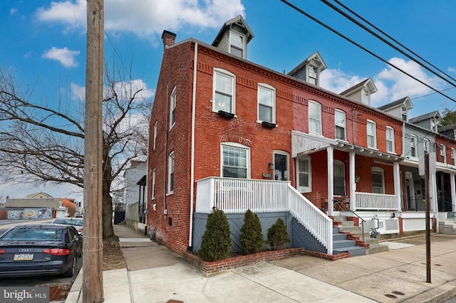 townhome / multi-family property with brick siding and a porch