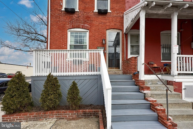 property entrance featuring brick siding and covered porch