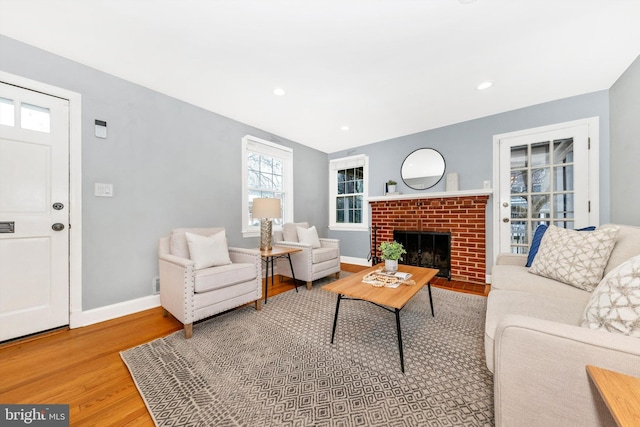 living room featuring recessed lighting, a brick fireplace, baseboards, and wood finished floors