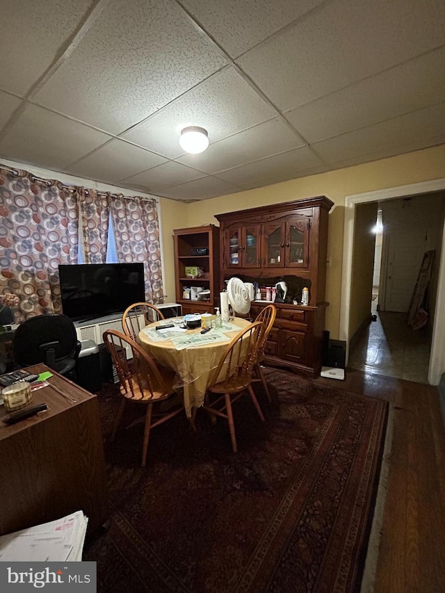 dining room featuring a drop ceiling and dark wood-type flooring