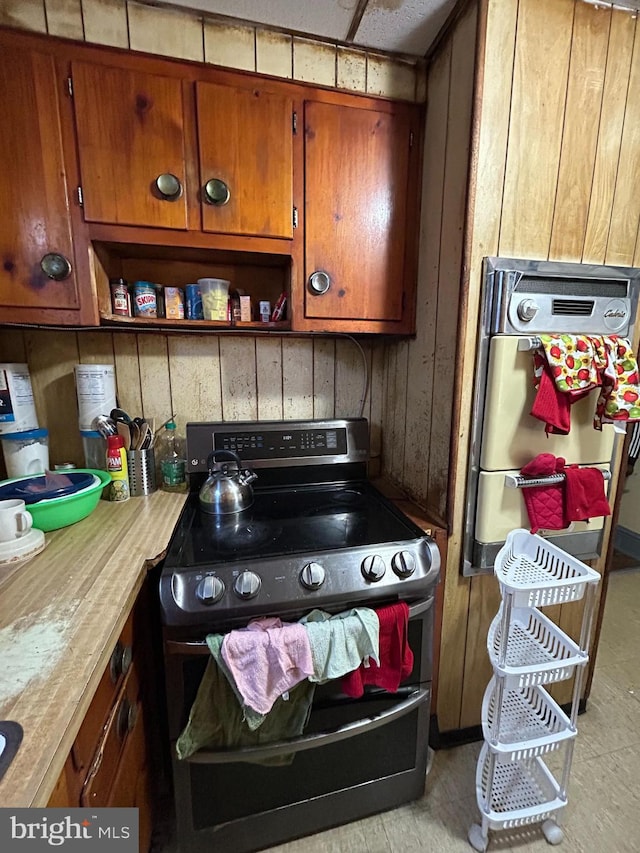 kitchen featuring brown cabinetry, stainless steel electric stove, light countertops, and open shelves