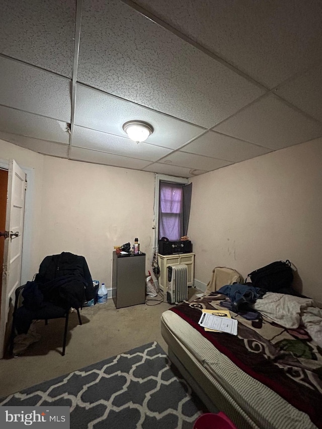 bedroom with a paneled ceiling and refrigerator