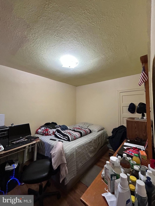 bedroom featuring a textured ceiling and wood finished floors