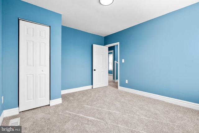 unfurnished bedroom featuring light carpet and a closet