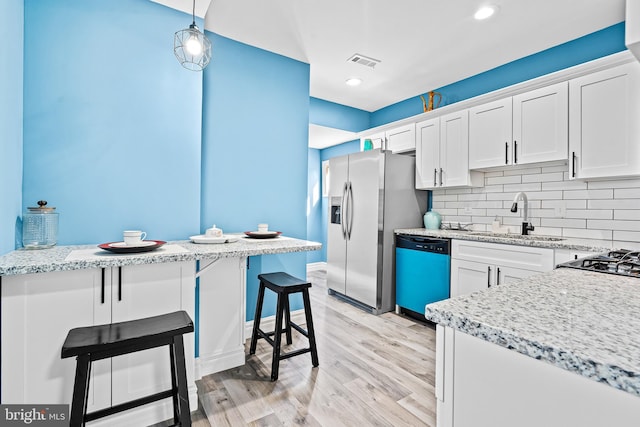 kitchen with pendant lighting, white cabinets, sink, and dishwasher