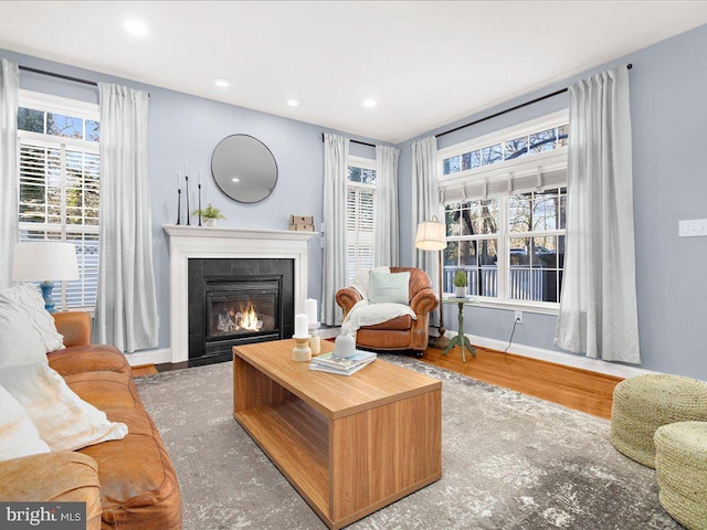 living room featuring a tiled fireplace, plenty of natural light, wood finished floors, and recessed lighting