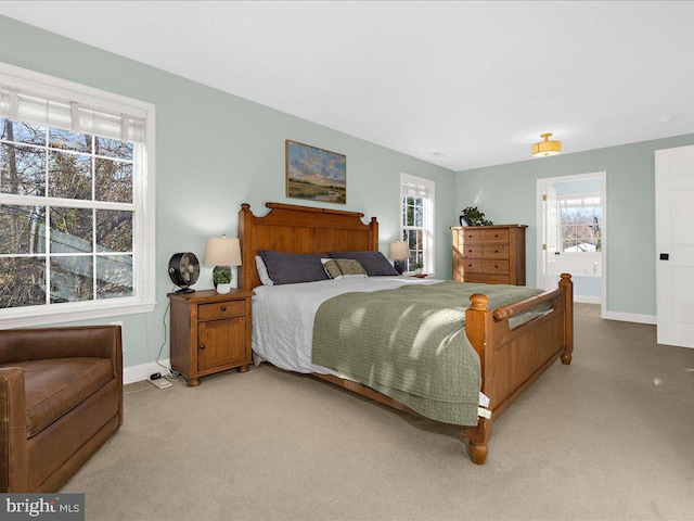 bedroom with baseboards, ensuite bathroom, and light carpet