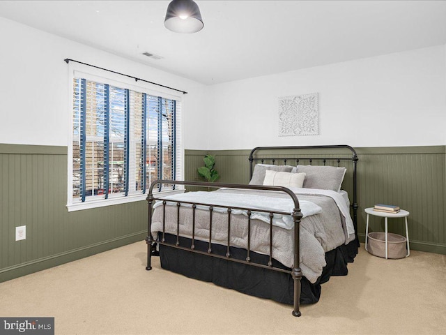 carpeted bedroom with visible vents and wainscoting