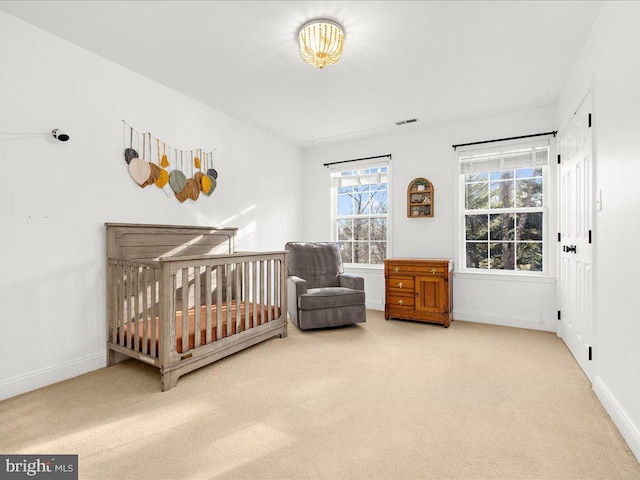 carpeted bedroom with visible vents, a crib, and baseboards