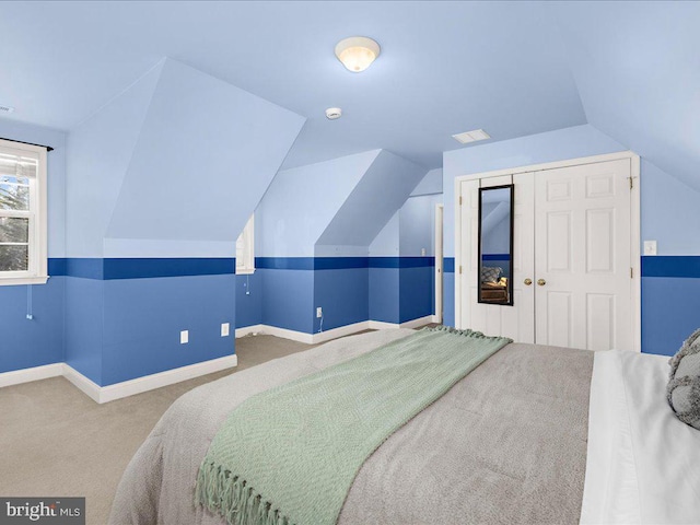 carpeted bedroom with a closet, baseboards, and vaulted ceiling