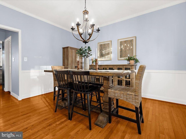 dining area featuring a notable chandelier, crown molding, baseboards, and wood finished floors