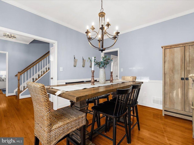 dining room with stairway, wood finished floors, visible vents, and ornamental molding