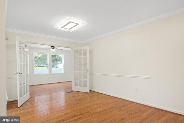 empty room featuring light wood-type flooring, visible vents, ornamental molding, and french doors