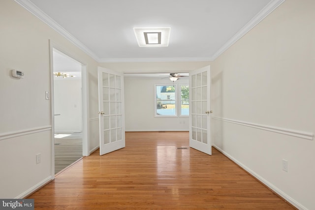 empty room with light wood-style flooring, baseboards, crown molding, and french doors