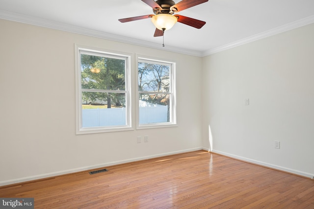 spare room with light wood-type flooring, visible vents, baseboards, and crown molding