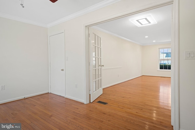 spare room with baseboards, hardwood / wood-style floors, and crown molding