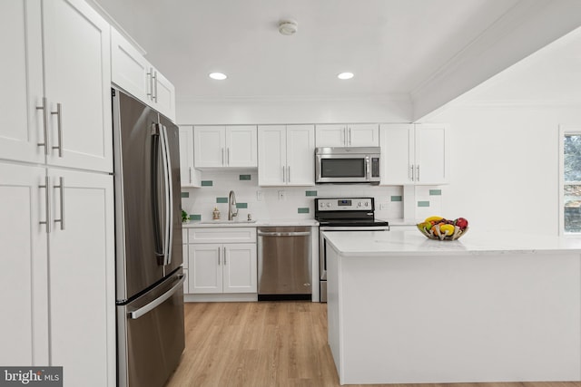 kitchen with appliances with stainless steel finishes, a sink, white cabinetry, and crown molding