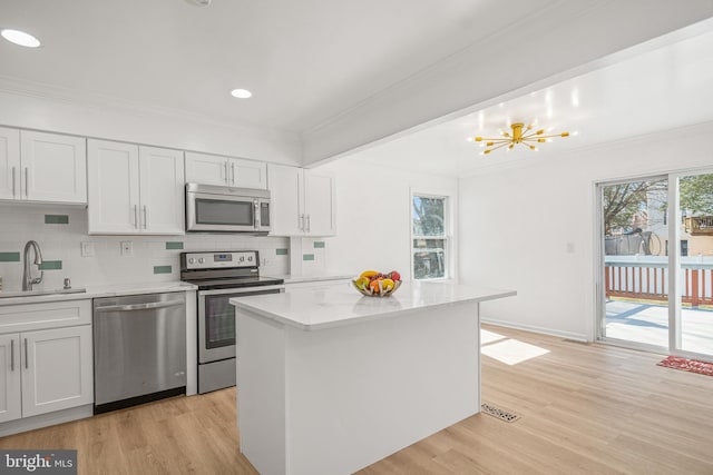 kitchen featuring tasteful backsplash, appliances with stainless steel finishes, crown molding, light wood-type flooring, and a sink