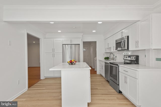 kitchen featuring stainless steel appliances, white cabinetry, light wood-style flooring, and a center island