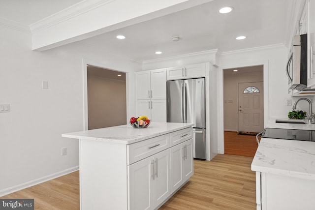 kitchen with stainless steel appliances, white cabinetry, and light wood-style flooring