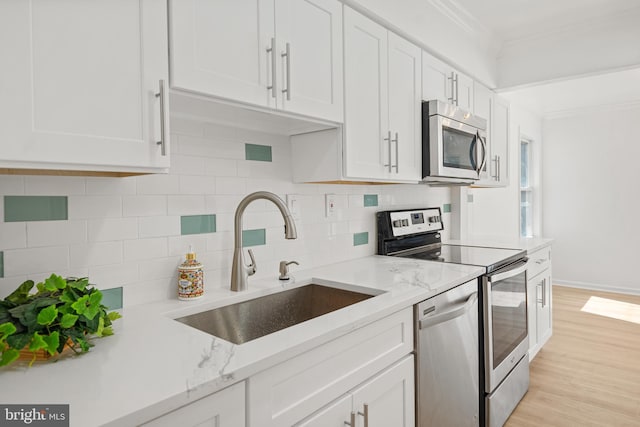 kitchen with crown molding, white cabinetry, stainless steel appliances, and a sink