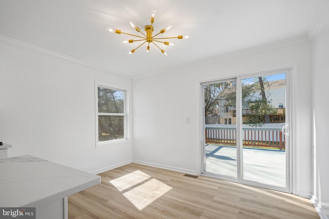 unfurnished dining area with a chandelier, ornamental molding, light wood-style flooring, and a healthy amount of sunlight