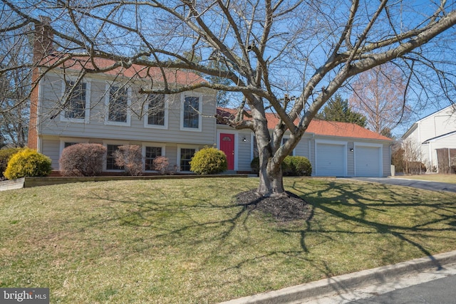 tri-level home featuring aphalt driveway, an attached garage, and a front yard