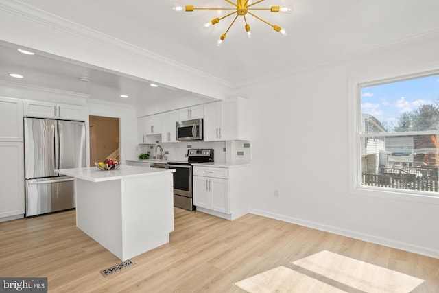 kitchen featuring light wood-style floors, visible vents, stainless steel appliances, and crown molding