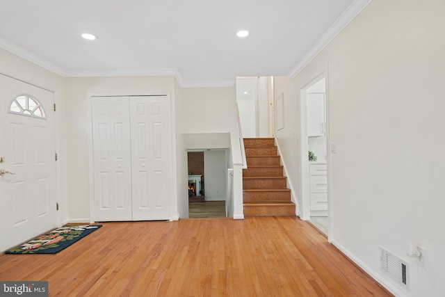 entryway featuring stairway, visible vents, light wood finished floors, and ornamental molding