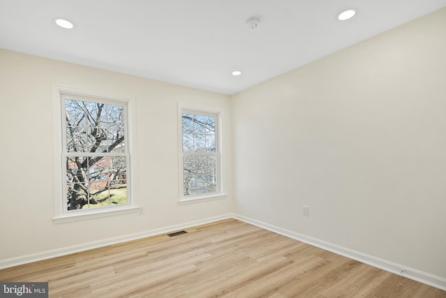 spare room with baseboards, plenty of natural light, visible vents, and light wood-style floors