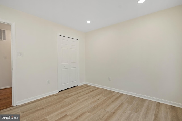 unfurnished bedroom with baseboards, a closet, recessed lighting, and light wood-style floors