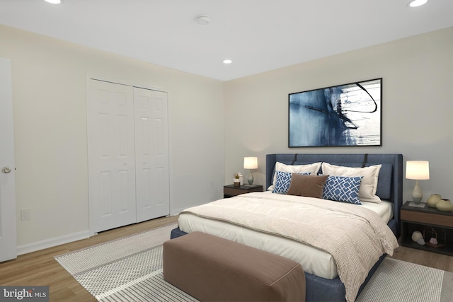 bedroom with a closet, baseboards, wood finished floors, and recessed lighting