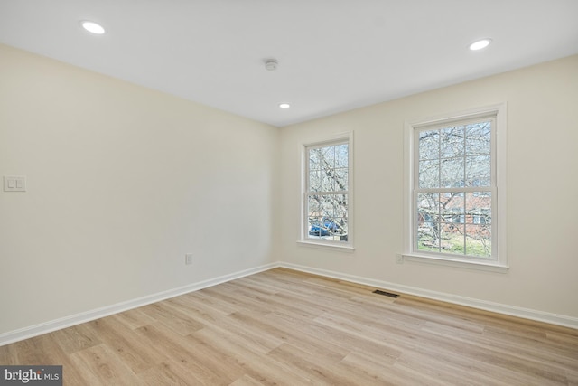 unfurnished room featuring light wood-type flooring, visible vents, baseboards, and recessed lighting