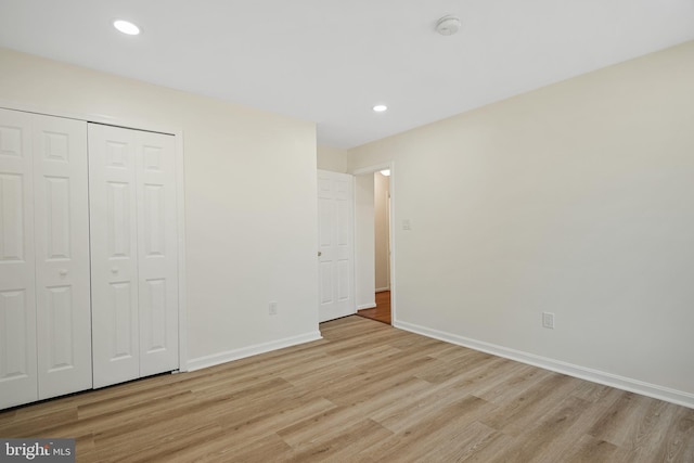 unfurnished bedroom featuring baseboards, a closet, and light wood-style floors