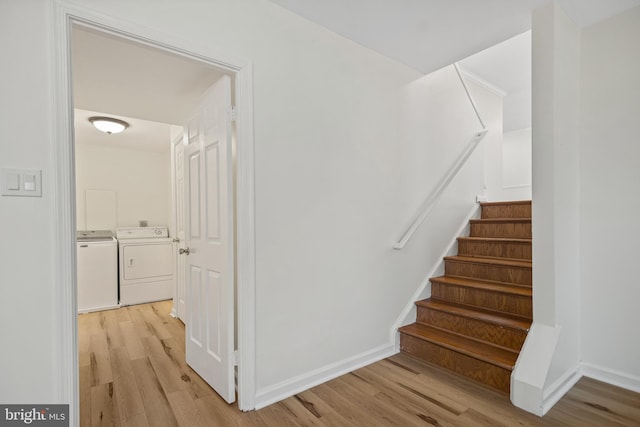 staircase with wood finished floors, washing machine and dryer, and baseboards