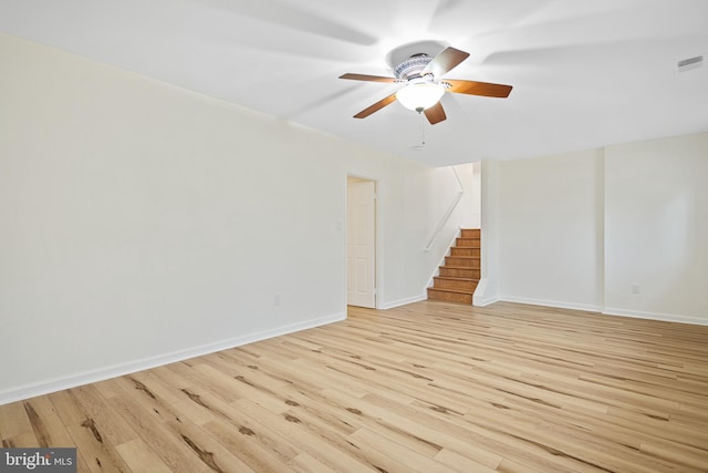 spare room featuring ceiling fan, visible vents, baseboards, stairway, and light wood finished floors