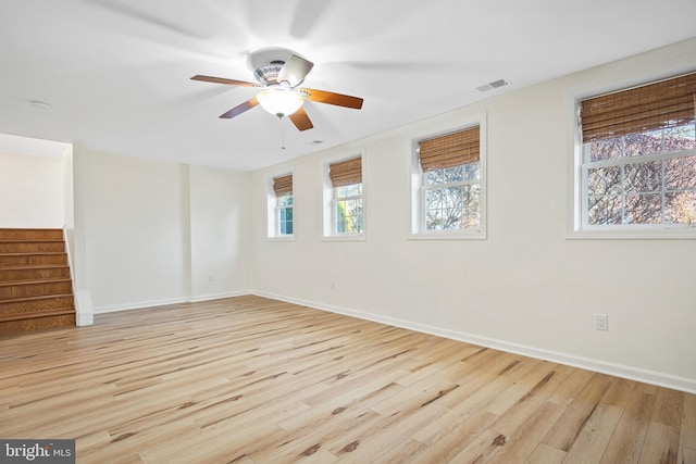 empty room with ceiling fan, visible vents, baseboards, stairway, and light wood-type flooring