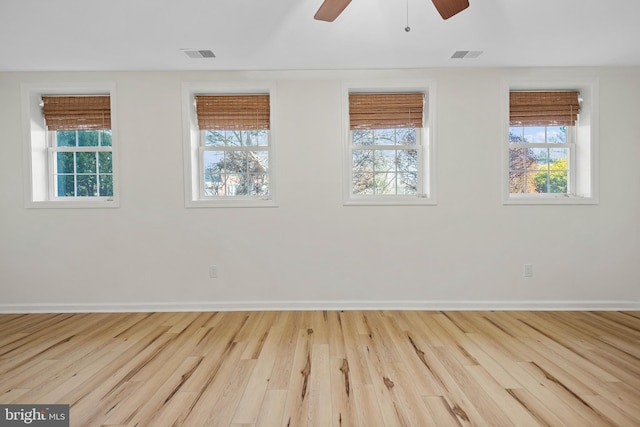 unfurnished room featuring a ceiling fan, wood finished floors, visible vents, and baseboards