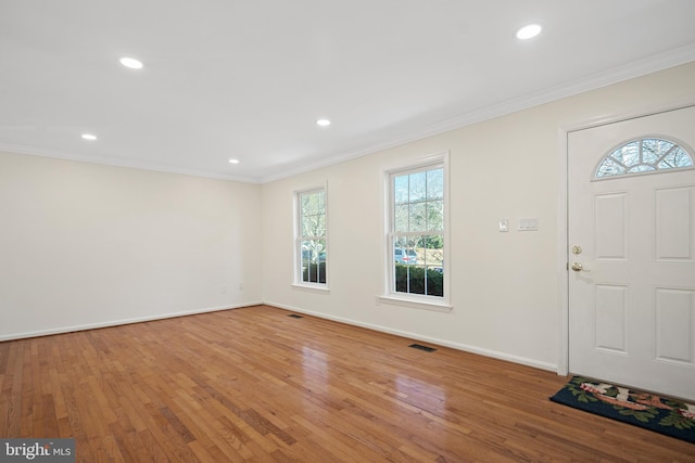 entrance foyer with ornamental molding, baseboards, visible vents, and hardwood / wood-style floors