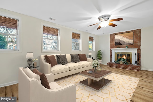 living room with a brick fireplace, wood finished floors, and a wealth of natural light