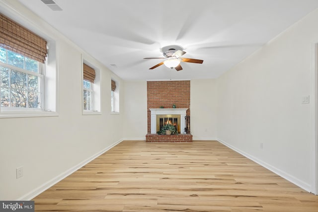 unfurnished living room featuring ceiling fan, visible vents, baseboards, light wood-type flooring, and a brick fireplace